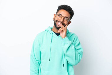 Genç Brezilyalı bir adam beyaz arka planda izole edilmiş bir şekilde bakarken bir fikir düşünüyor.