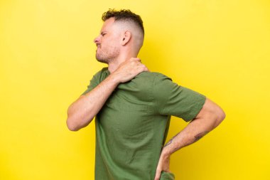 Beyaz tenli yakışıklı, sarı arka planda izole edilmiş, omuz ağrısından muzdarip, çaba sarf ettiği için.