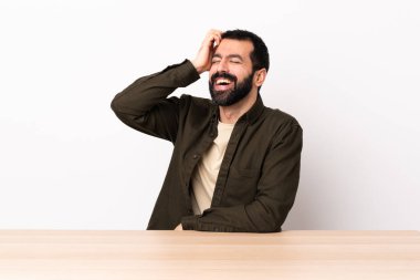Masada sakallı, beyaz bir adam gülümsüyor..