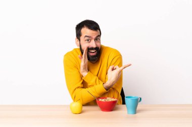 Kafkasyalı bir adam bir masada kahvaltı yapıyor. Yan tarafı göstererek ürünü sunuyor ve bir şeyler fısıldıyor..