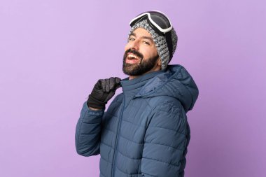 İzole edilmiş mor arka planda snowboard gözlüklü kayakçı.
