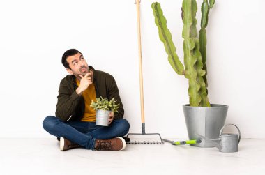 Bahçıvan içeride yerde oturuyor. Şüpheleri var ve kafası karışık.