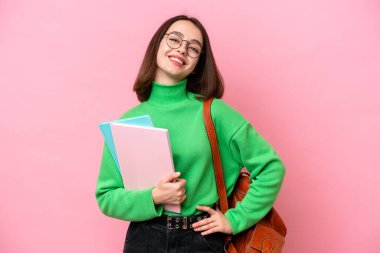 Genç öğrenci Ukraynalı kadın pembe arka planda izole edilmiş, kolları kalçasında ve gülümsüyor.