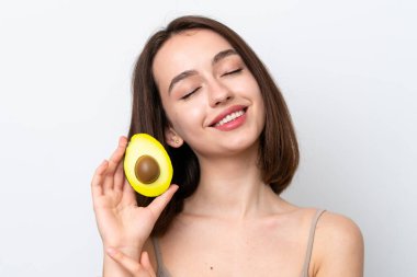 Genç Ukraynalı bir kadın beyaz arka planda izole edilmiş, elinde avakado tutarken gülümsüyor. Portreyi kapat