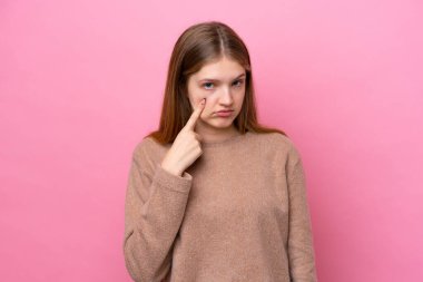 Pembe arka planda izole edilmiş genç Rus kız bir şey gösteriyor.