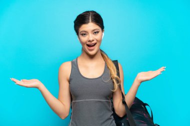 Spor çantalı genç Rus kız mavi arka planda izole edilmiş ve şok olmuş bir yüz ifadesi var.