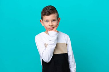 Küçük çocuk mavi arka planda izole edilmiş düşünüyor.