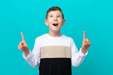 Küçük çocuk mavi arka planda izole edilmiş. Şaşırmış ve yukarı bakıyor.