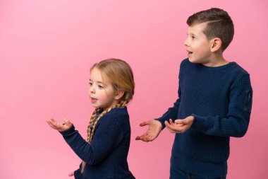 Küçük Kafkas kardeşler pembe arka planda yalıtılmış ve şaşırmış bir yüz ifadesi var.