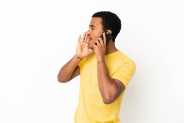 Beyaz arka planda cep telefonu kullanan Afro-Amerikalı yakışıklı adam ağzı sonuna kadar açık bağırıyor.