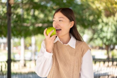 Dışarıdaki güzel Çinli kadın elma yiyor.
