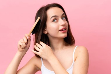 Genç Ukraynalı kadın pembe arka planda saç tarağıyla izole edilmiş.