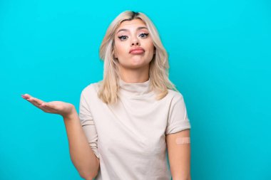 Mavi arka planda yara bandı takan genç Rus kadın omuzlarını kaldırırken şüpheli hareketlerde bulunuyor.