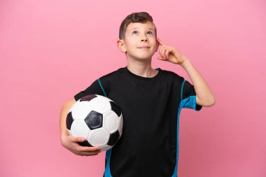 Kafkas futbolcu çocuk pembe arka planda izole edilmiş. Şüpheleri ve düşünceleri var.