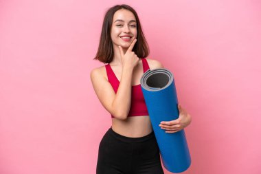 Genç sporcu Ukraynalı kadın yoga derslerine gidiyor pembe arka planda izole edilmiş bir minderi tutarken mutlu ve gülümsüyor.
