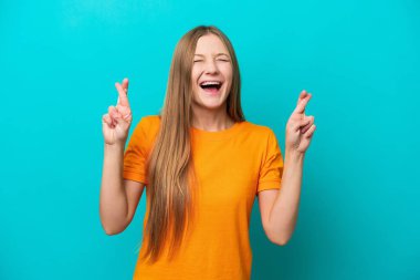 Genç Rus kadın mavi arka planda izole edilmiş ve parmakları çapraz