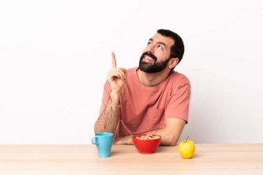 Masada kahvaltı eden beyaz bir adam harika bir fikre işaret ediyor..