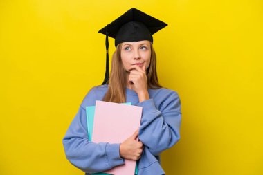 Genç Rus öğrenci kadın sarı arka planda izole edilmiş ve yukarı bakıyor.