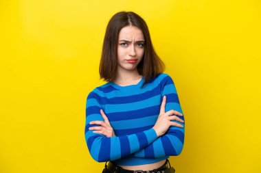 Sarı arka planda izole edilmiş genç Ukraynalı kadın üzgün hissediyor