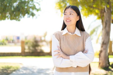 Dışarıdaki güzel Çinli kadın gülümserken yukarı bakıyor.