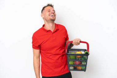 Beyaz arka planda izole edilmiş yiyecek dolu bir alışveriş sepeti tutan beyaz bir adam.