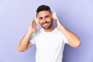 Mor arka planda izole edilmiş beyaz adam müzik dinliyor.