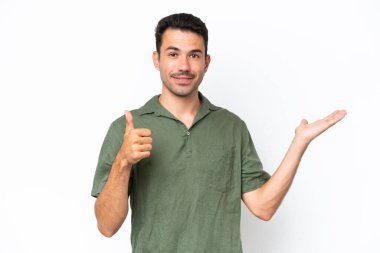 İzole edilmiş beyaz arka plan üzerinde genç yakışıklı bir adam. Avucunun içinde hayali bir şey tutuyor. Bir ilan vermek için.