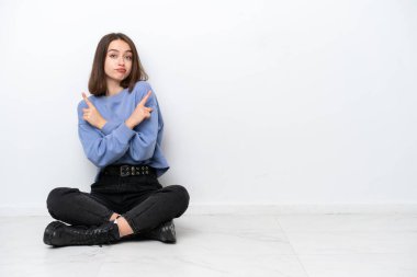 Genç Ukraynalı kadın, beyaz arka planda izole bir şekilde yerde oturuyor.