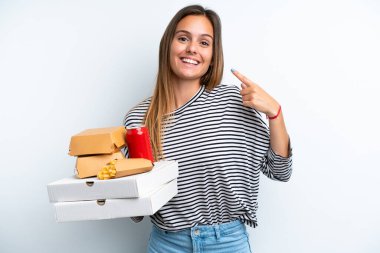 Beyaz arka planda izole edilmiş fast food tutan beyaz bir kadın baş parmak işareti yapıyor.