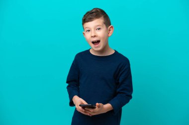 Küçük çocuk mavi arka planda izole edildi. Şaşırdı ve bir mesaj gönderdi.