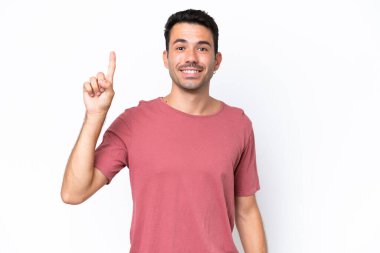Soyutlanmış beyaz arka planı olan yakışıklı genç adam harika bir fikre işaret ediyor.