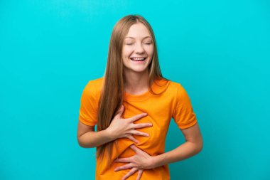 Mavi arka planda izole edilmiş genç bir Rus kadın. Çok gülümsüyor.