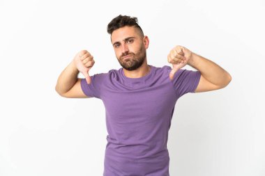 Beyaz arka planda izole edilmiş beyaz bir adam baş parmağını iki eliyle aşağı gösteriyor.