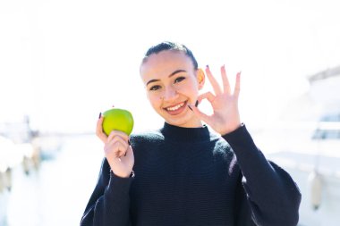 Açık havada elmalı genç Faslı kız parmaklarıyla 