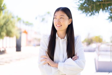 Dışarıdaki güzel Çinli kadın gülümserken yukarı bakıyor.