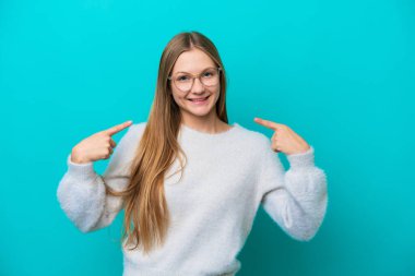 Mavi arka planda izole edilmiş genç bir Rus kadın baş parmak işareti yapıyor.