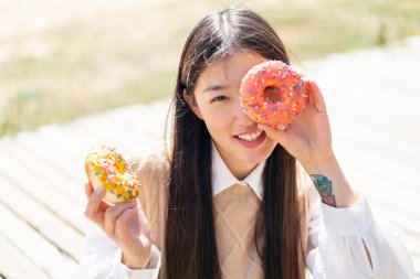Dışarıdaki genç Çinli kadın, elinde donutlarla.