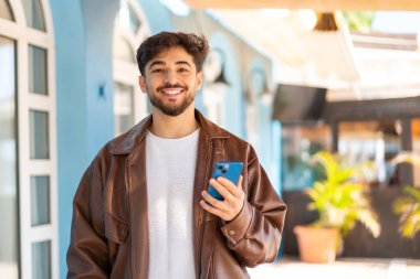 Dışarıda cep telefonu kullanan yakışıklı bir Arap.