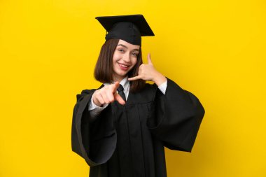 Genç üniversite mezunu Ukraynalı bir kadın sarı arka planda izole edilmiş telefon hareketi yapıyor ve ön tarafı işaret ediyor.