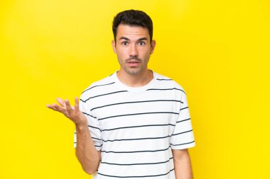 Soyutlanmış sarı arka planda genç yakışıklı bir adam şüpheli hareketler yapıyor.