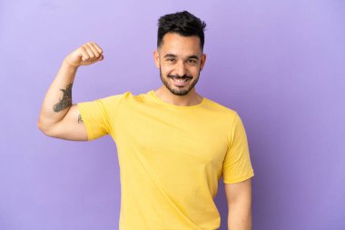 Mor arka planda izole genç beyaz adam güçlü bir jest yapıyor.