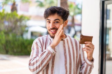 Yakışıklı bir Arap dışarıda cüzdanını tutuyor ve bir şeyler fısıldıyor.