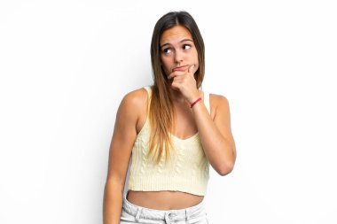 Beyaz arka planda izole edilmiş genç beyaz bir kadın. Şüpheleri var ve kafası karışmış bir yüz ifadesi var.