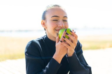 Dışarıda elinde elma tutan Faslı genç bir kız.