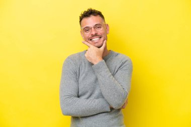 Sarı arka planda izole edilmiş genç beyaz yakışıklı adam mutlu ve gülümsüyor.