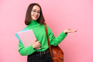 Genç Ukraynalı bir kadın pembe arka planda izole edilmiş, davet edilmek için ellerini yana uzatıyor.