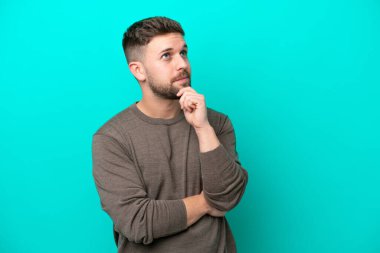 Kafkasyalı genç adam mavi arka planda izole edilmiş ve yukarı bakıyor.