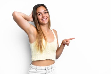 Beyaz arka planda izole edilmiş genç beyaz kadın şaşırmış ve işaret ediyor.