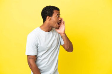 Sarı arka planda ağzı sonuna kadar açık bağıran Afro-Amerikalı yakışıklı bir adam.