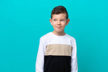 Küçük çocuk mavi arka planda izole edilmiş. Taraf tutarken şüphe duyuyor.